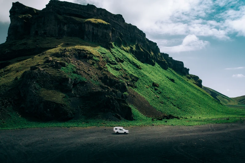 Camper 4x4 bianco che percorre strade sterrate ai piedi di una montagna in Islanda