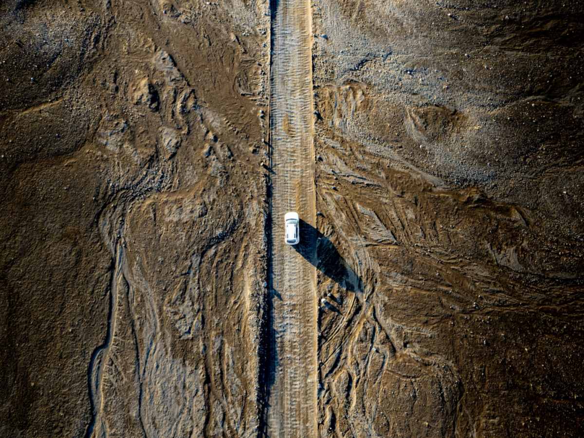 Drone view of a white camper cruising through the remote areas of the Highlands of Iceland