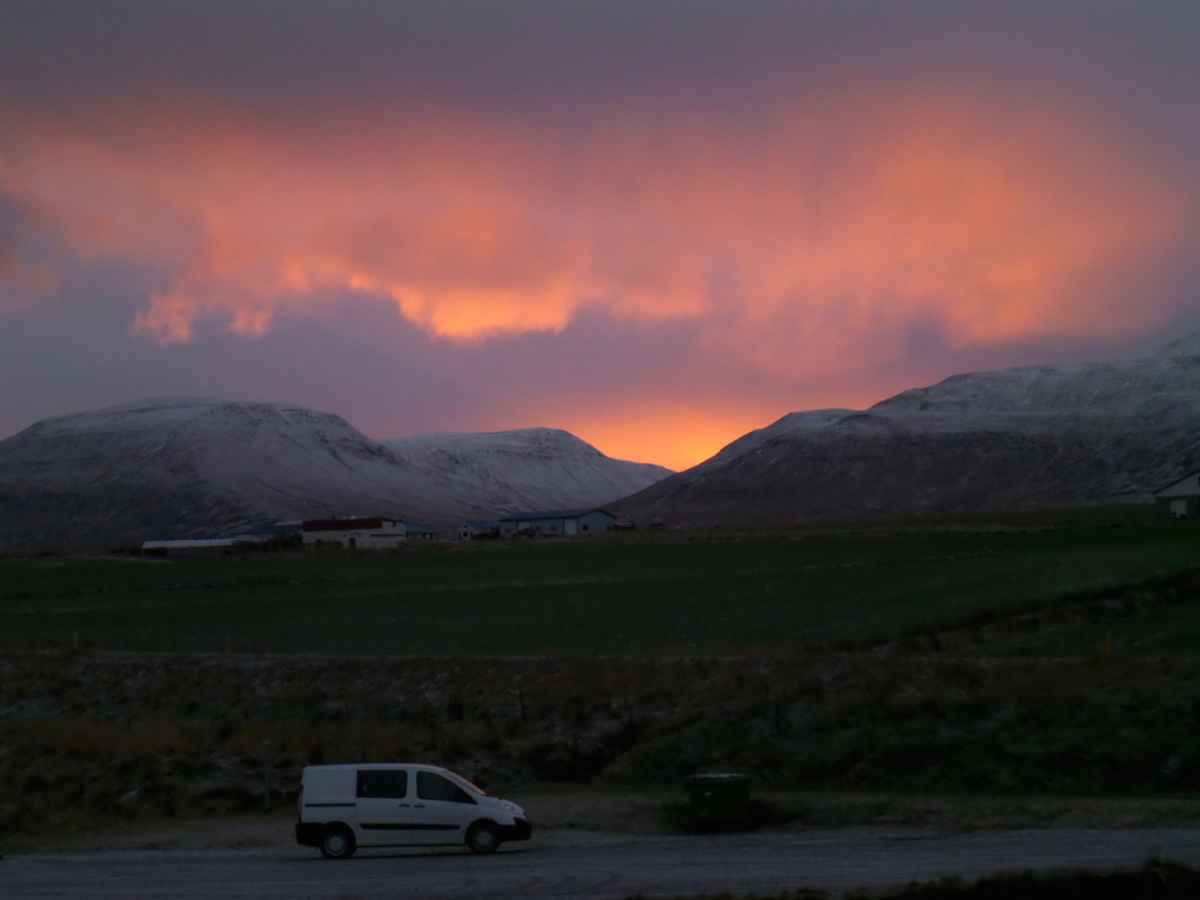 Campervan parked in Iceland with the midnight sun at the back