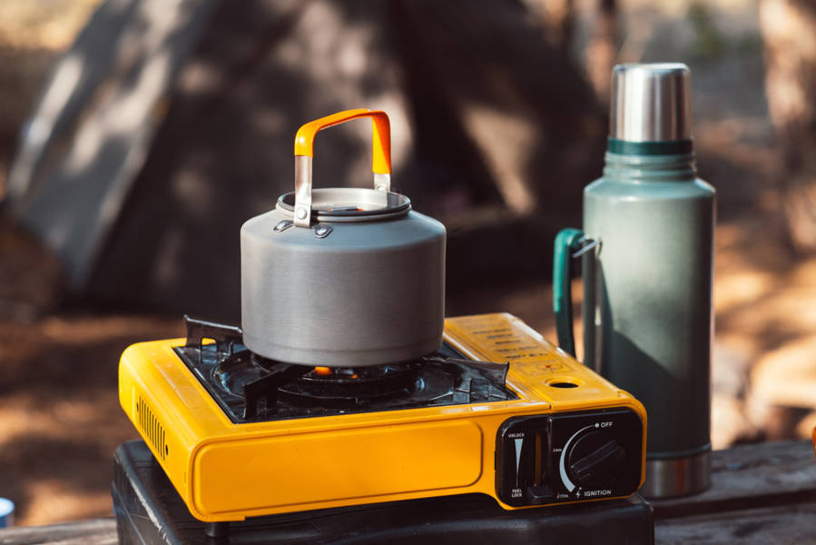 A portable camping stove and a boiler on a table