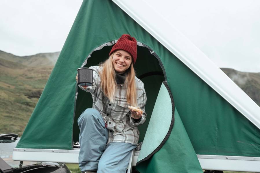 Young women eating breaking in her camping tent