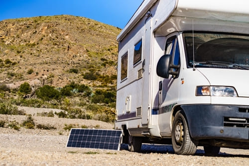 RV parked in a remote area using a portable solar power generator with solar panels for off-grid camping and energy efficiency.