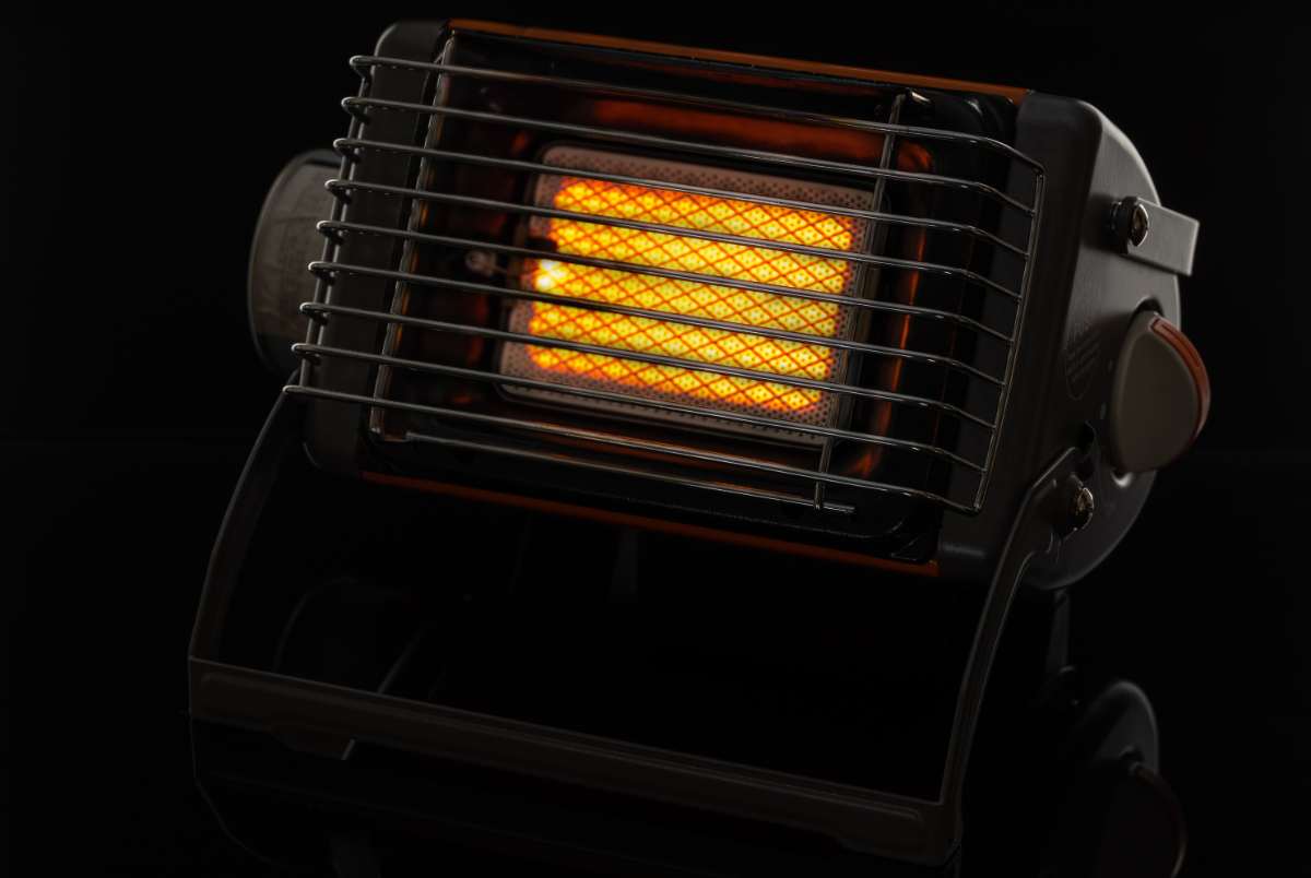 A close-up of a compact portable space heater with a glowing heating element, emitting warm light against a dark background. The device is designed for efficient heating in small spaces, making it a great addition to RV living during cold weather.