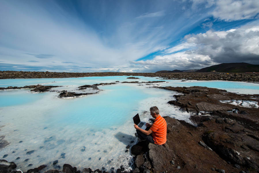 Man working remotely in Iceland sitting by a geothermal hot spring