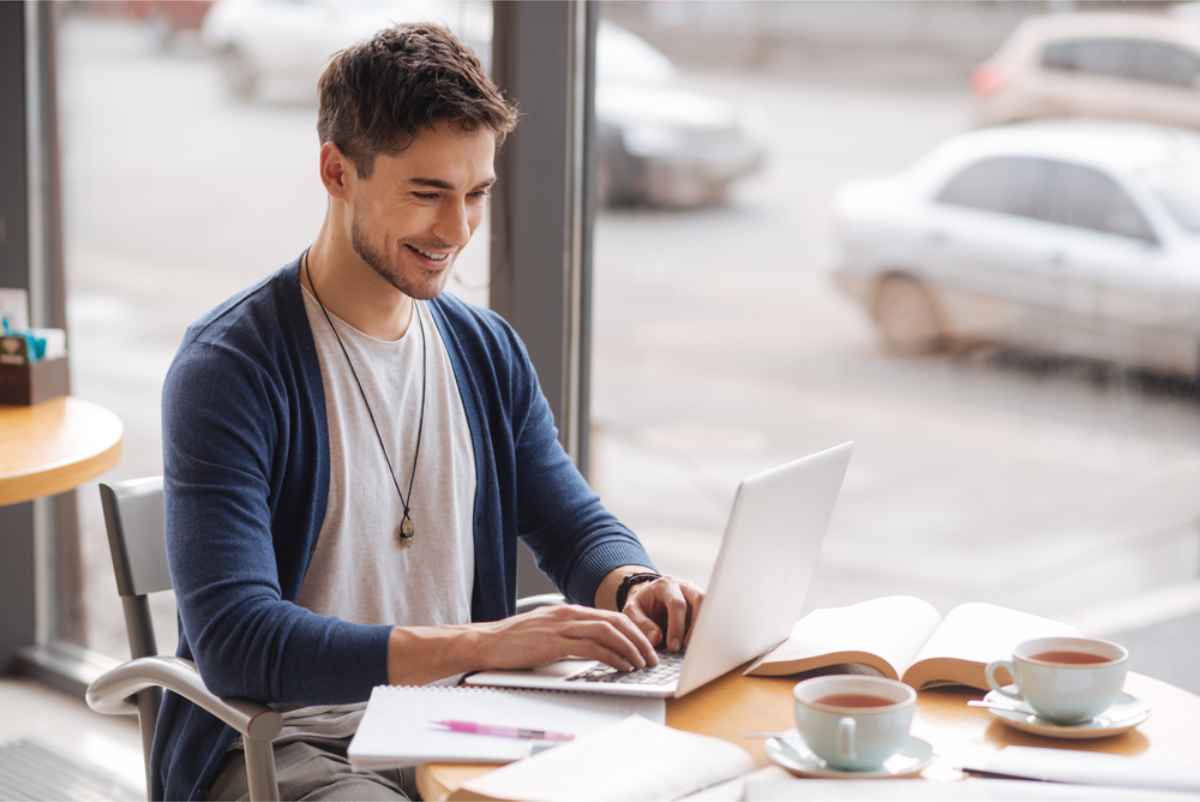 young man working from a cafeteria with his laptop