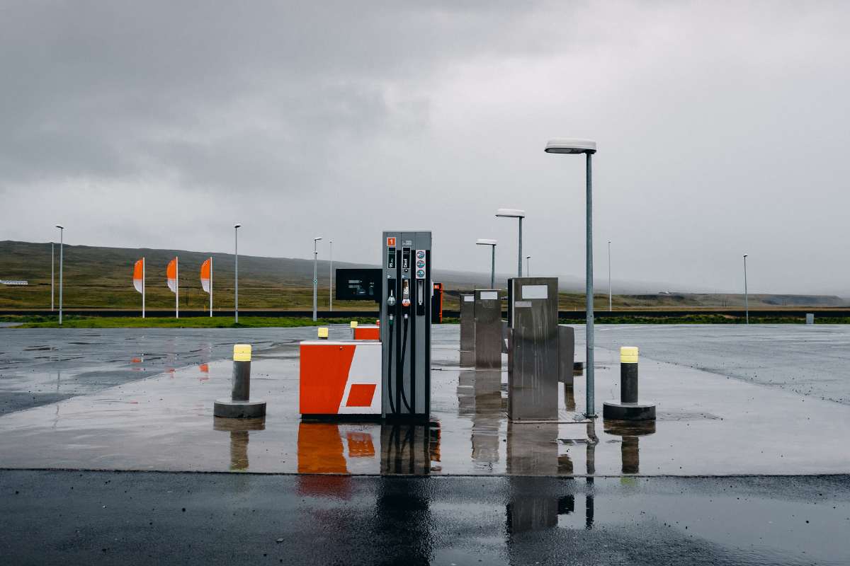 A nearly empty gas station in Iceland on a rainy day, with wet pavement reflecting the fuel pumps and surrounding lights. The image highlights one of the key considerations of RV travel in Iceland—fuel costs and availability in remote areas.