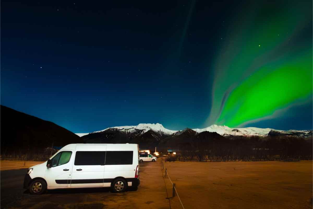 White campers parked in a campsite with the northern lights shining in the sky