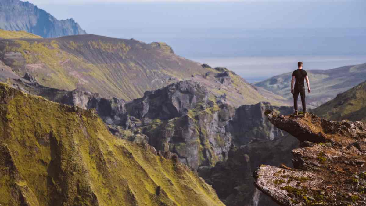 austurafretta hiking trail with a hiker standing on the edge of a cliff with panoramic views