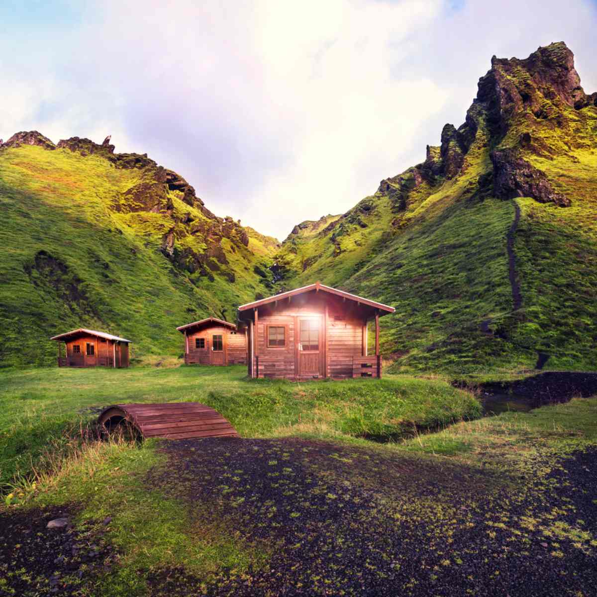 group of huts in the middle of moss covered mountains