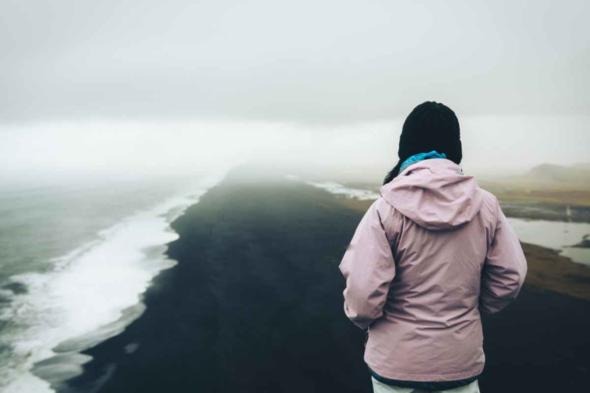 Tourist looking over Reyknisfjara black sand beach
