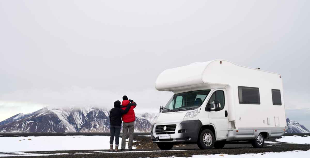 A couple taking in the view with their white RV rental in Iceland