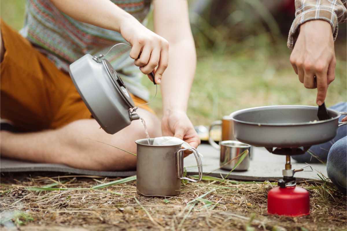two campers cooking with their portable burner