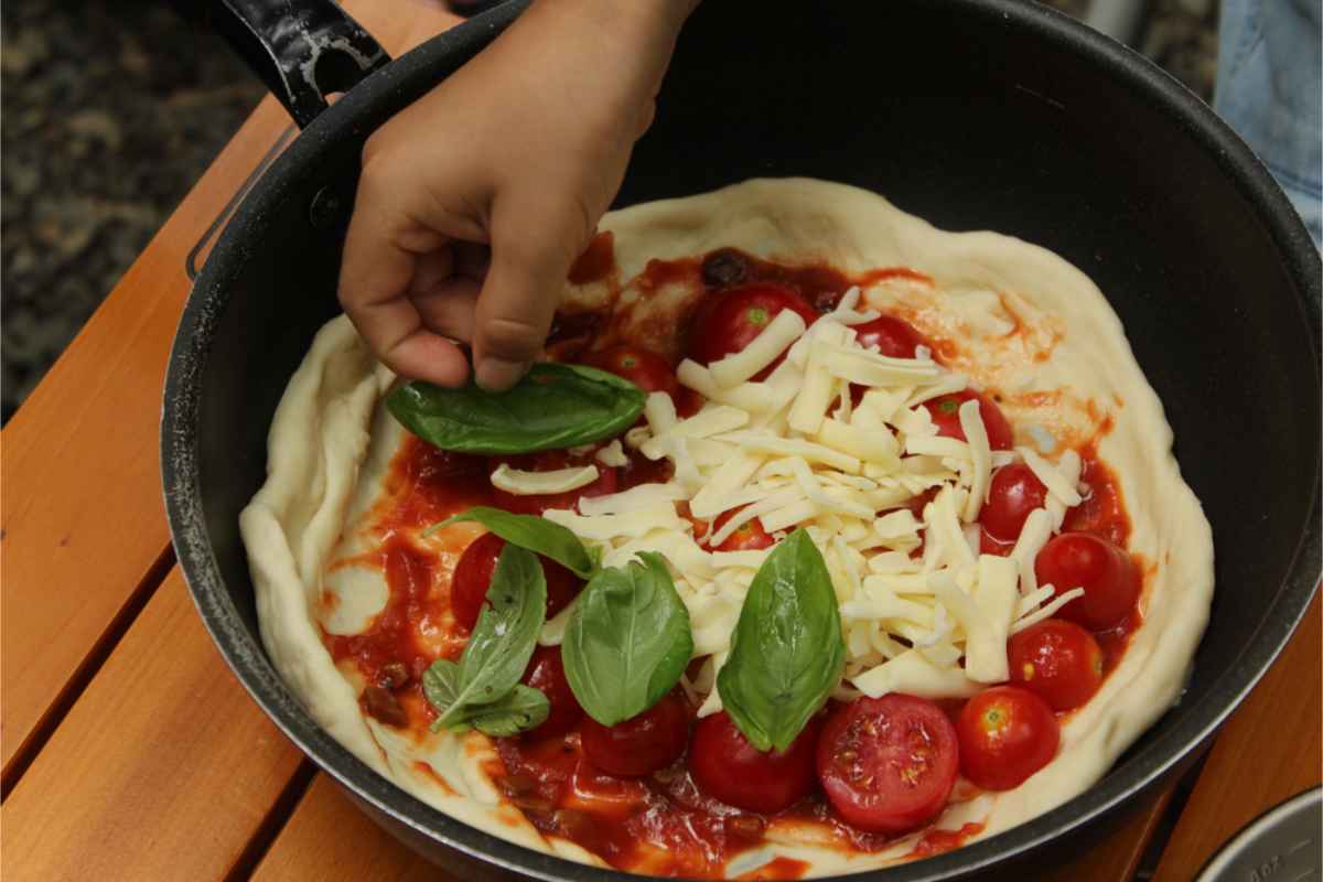 Pizza with tomato, basil, mozarella on a pot while camping