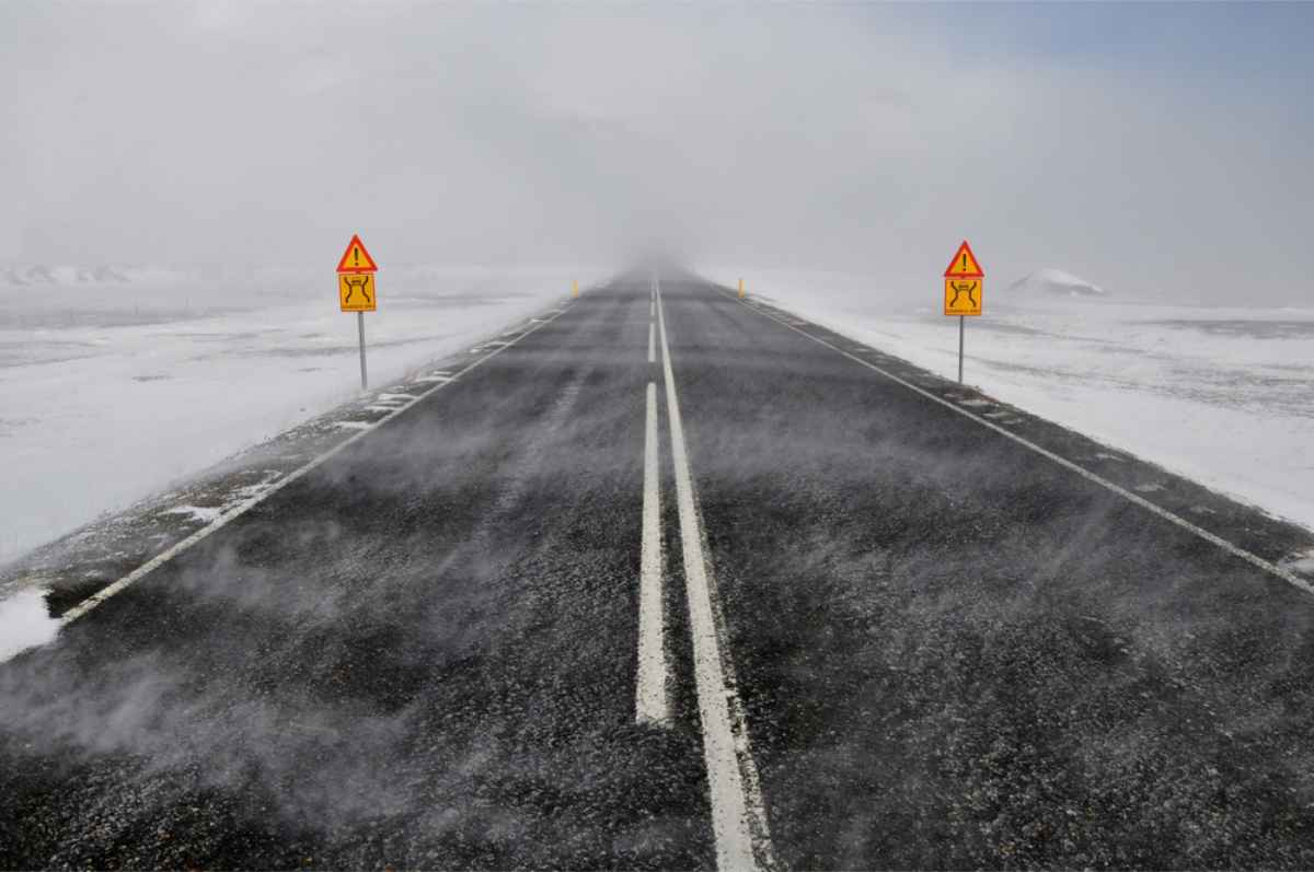 Icelandic road with snow and strong gusts of wind blowing