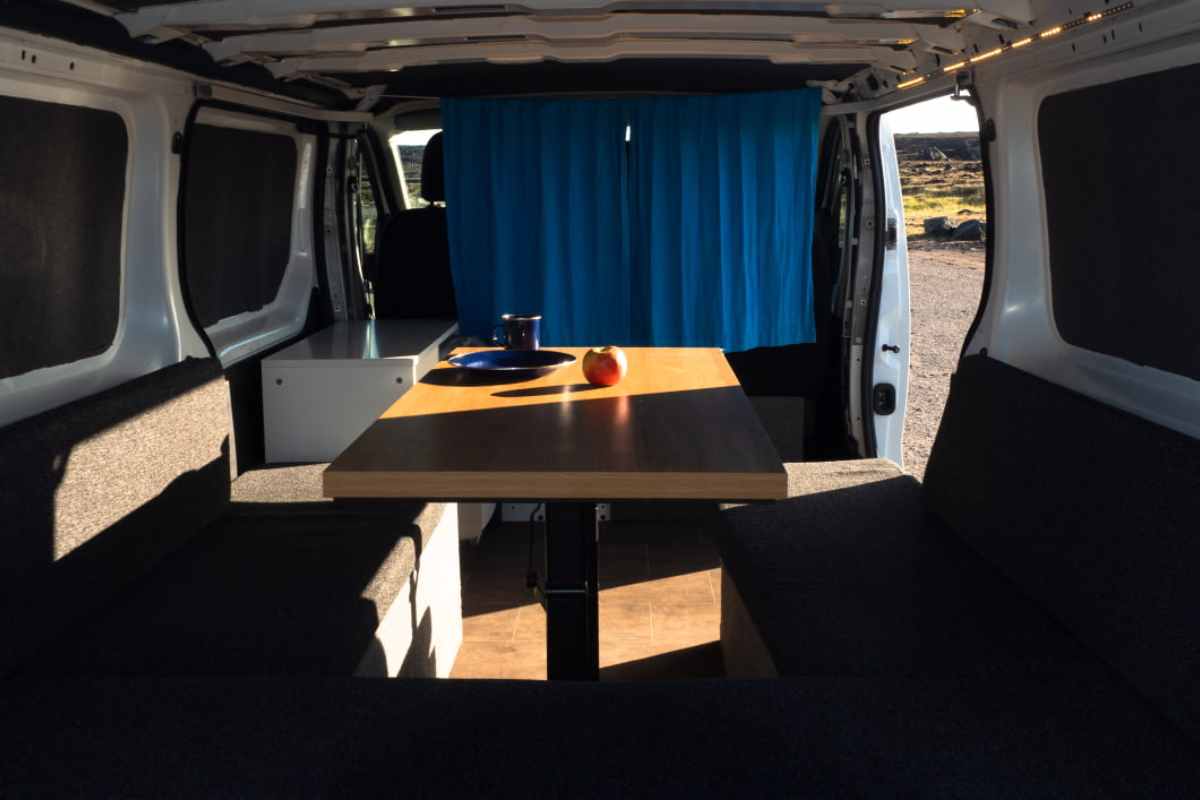 Inside view of a campervan in Iceland with a wooden table and seating area.