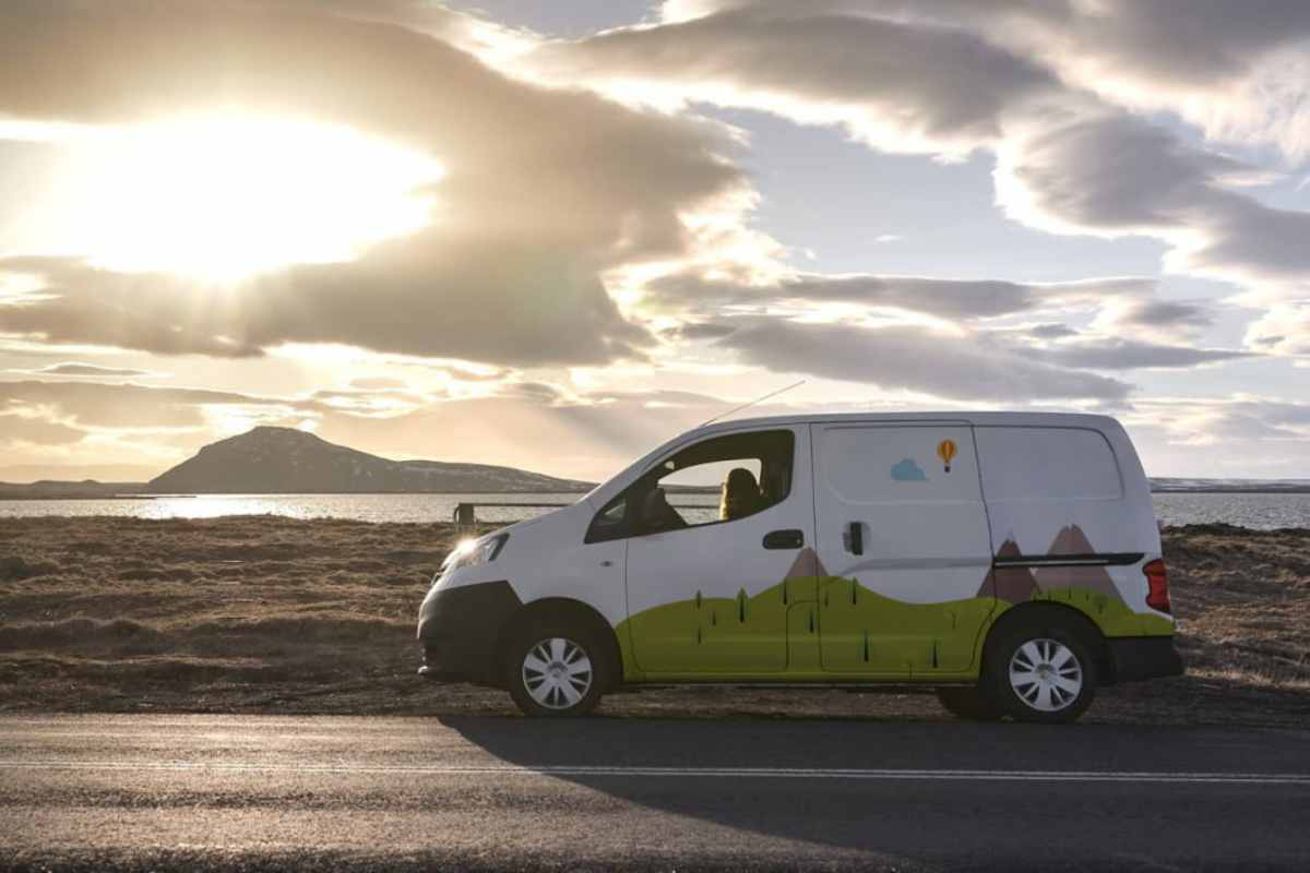 White campervan with colorful design parked by the sea during sunset in Iceland.