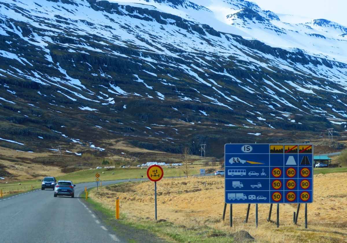 Road sign in Iceland showing national speed limits with mountains in the background.