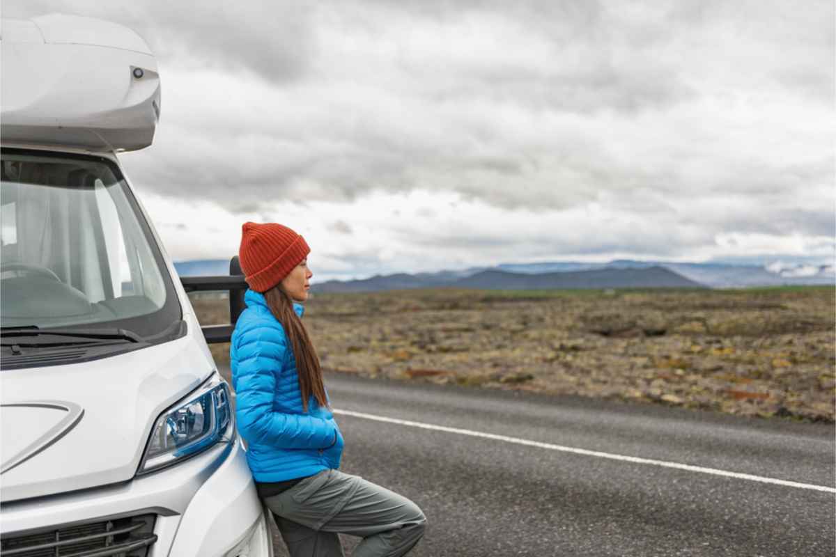 woman leaning onto her RV while on the road in Iceland