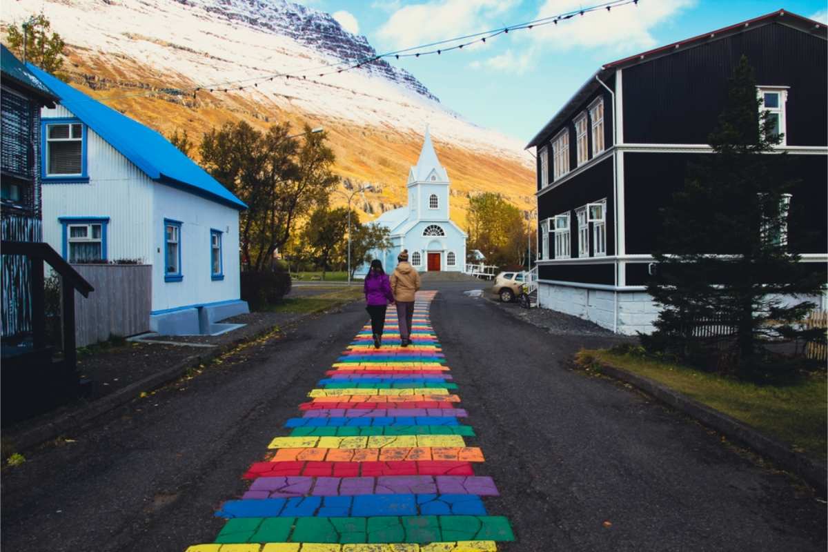 Rainbow road leading to a white church in Iceland