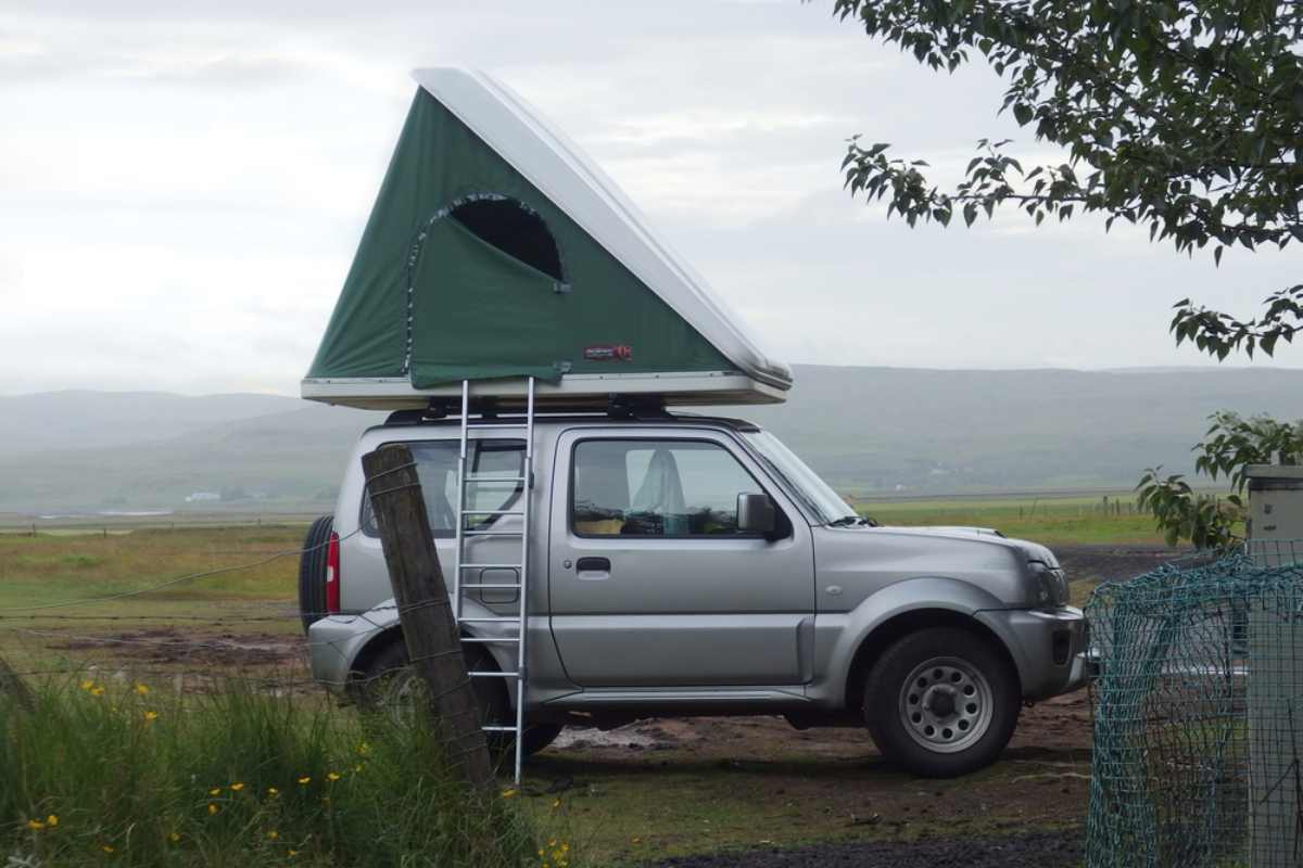 Why choose a rooftop tent in Iceland Small SUV with a rooftop tent parked in the Icelandic countryside on a cloudy day