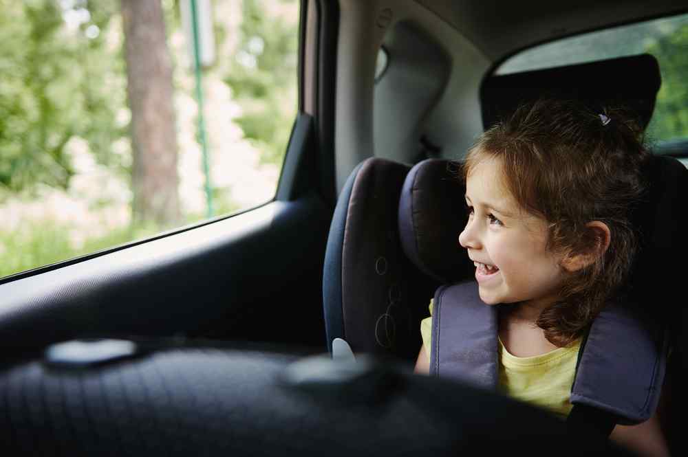 Booster seat Child sitting in a booster seat and looking out the car window.