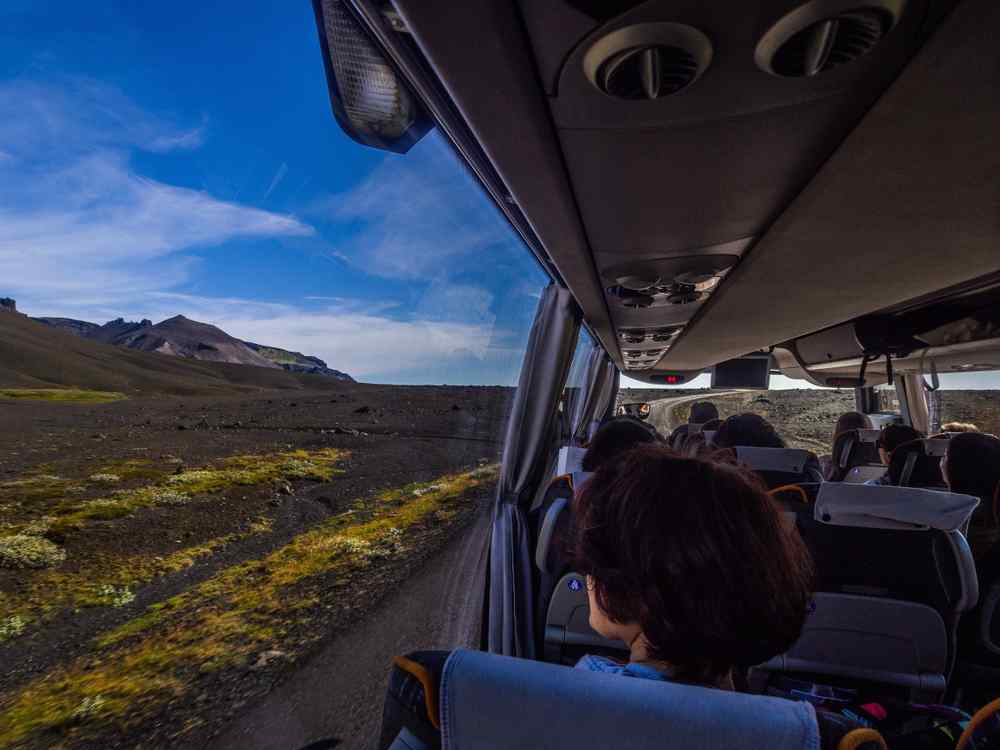 Bus driving in Iceland Passengers riding a tour bus through a volcanic landscape in Iceland.