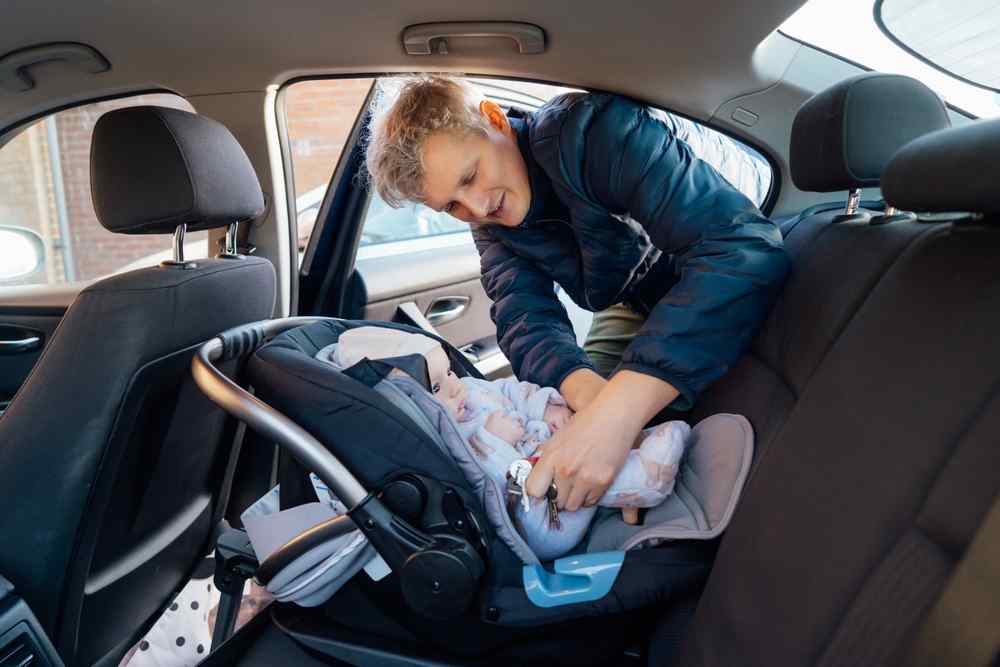 Rear facing Adult securing a baby in a rear-facing car seat.